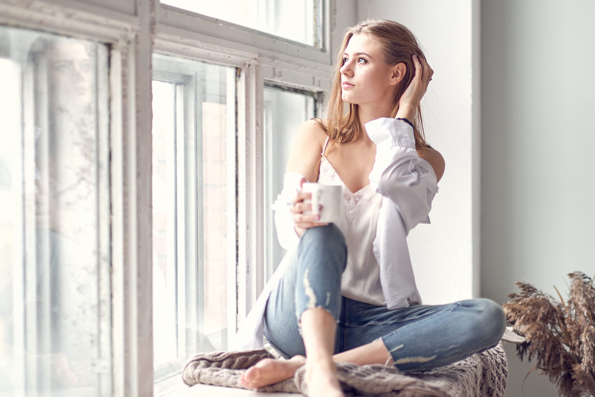 woman sitting on the windowsill and looking out the window